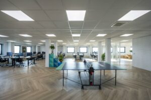Modern open kantoorinterieur aan de Joan Muyskenweg met bureaus, planten en een tafeltennistafel op de voorgrond.